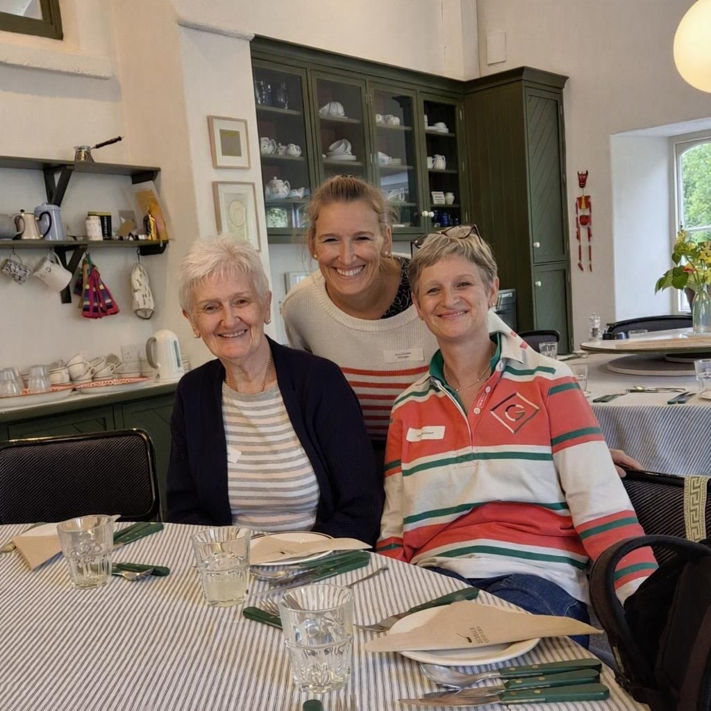 Sara with her mum and her sister, smiling around a table on a cookery course