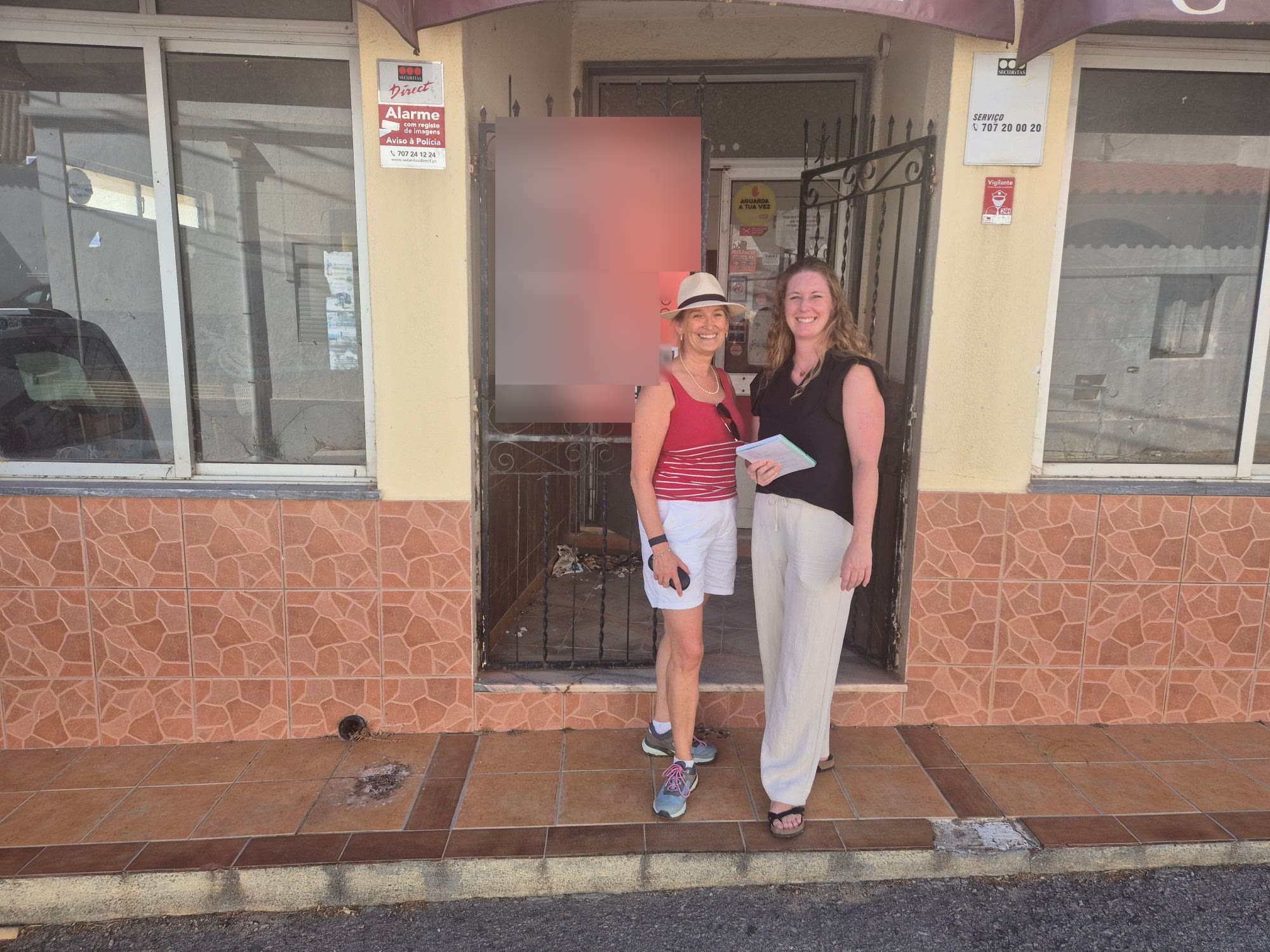 Sara and her project manager standing outside a property in Portugal, notebook in hand